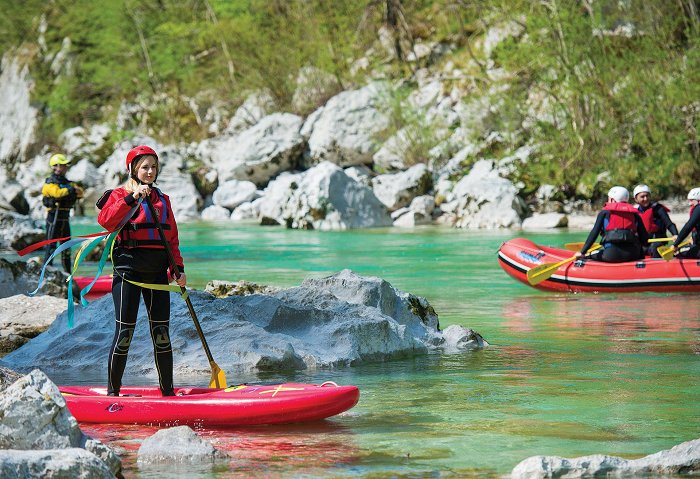 Una ragazza in piena attrezzatura sul SUP sul fiume verde smeraldo Isonzo