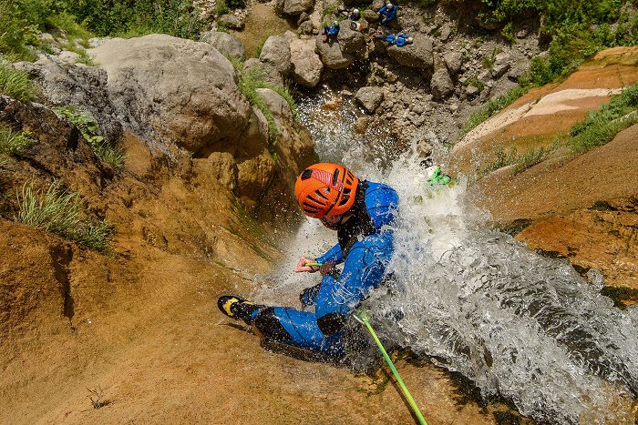 Canyonista scende dalla cascata con la corda dove un gruppo lo aspetta