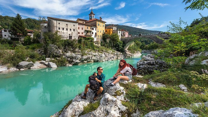 Das Paar genießt den Fluss Soča, der unter der Kanalbrücke fließt.