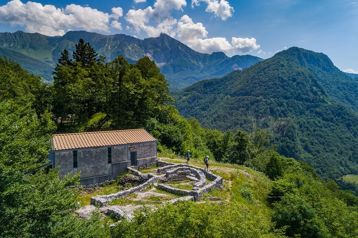 Pohodnika se sprehajata po ostalinah, v ozadju gora Krn