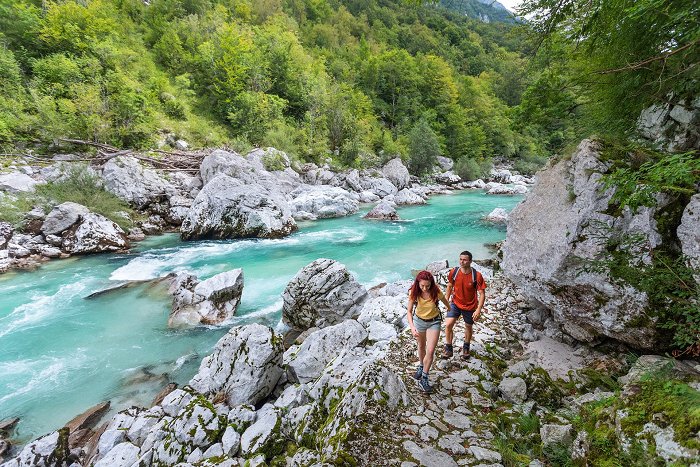 Pohodnika se sprehajata po Juliana Trail ob smaragdni reki Soči