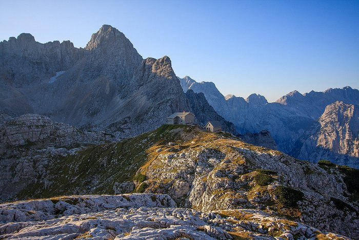 Blick auf die Berghütte Pogačnikov dom mit Bergen im Hintergrund