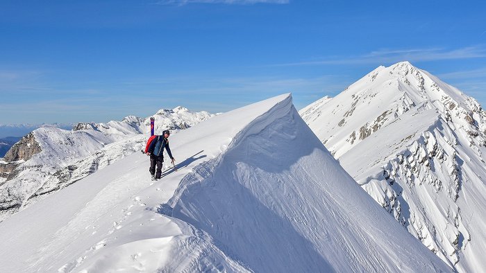 Turni smučar uživa v razgledu na vrhu zasnežene gore